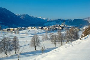 Winterliche Landschaft mit schneebedeckten Hügeln und dem Dorf St. Veit im Pongau.